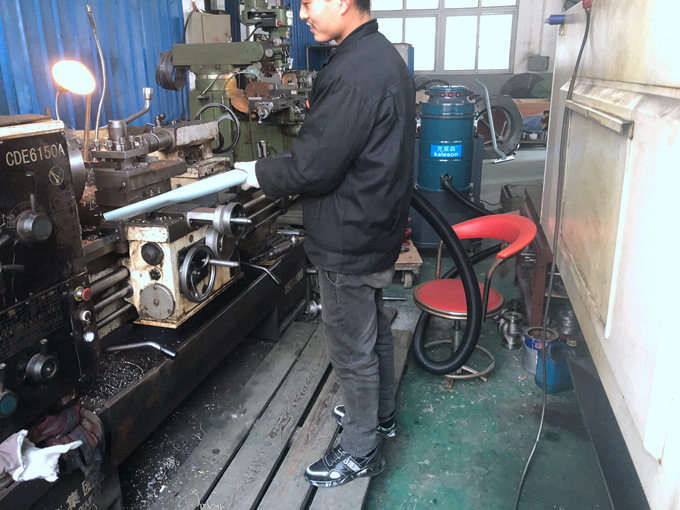 工人正在用大功率吸尘器吸车床上的铁渣